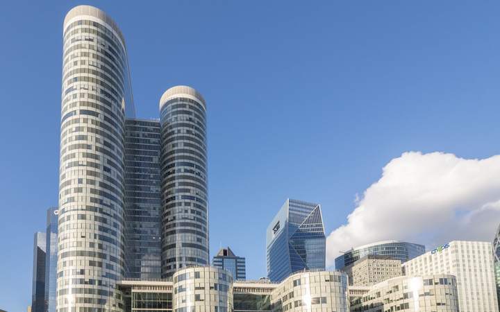 Tours de bureaux et esplanade piétonne d’un quartier d’affaires sous un ciel bleu