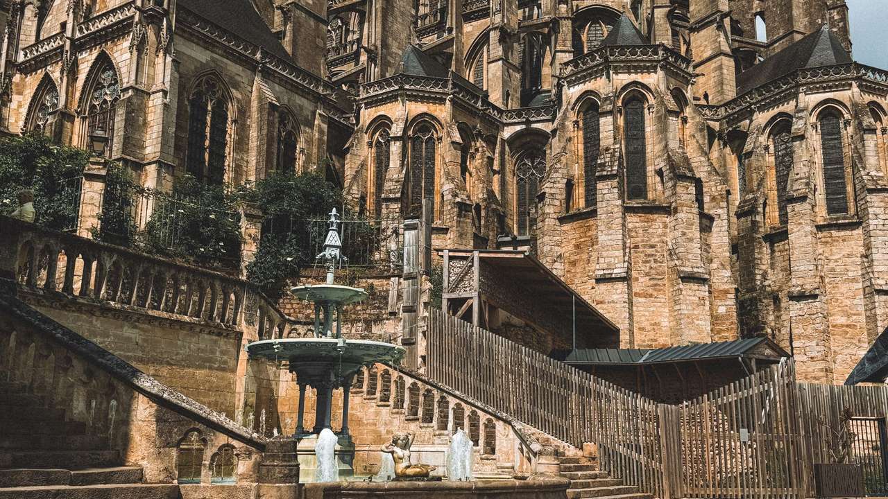Chevet gothique de la cathédrale du Mans, avec une fontaine et un escalier de pierre au premier plan