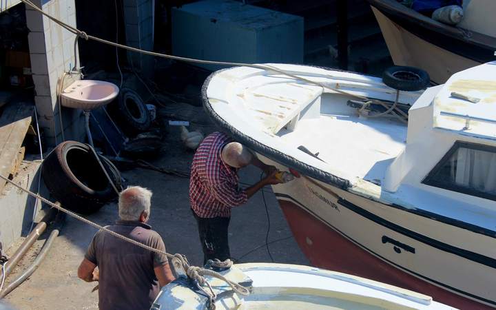 Deux hommes réparant la coque d’un bateau de plaisance dans un atelier de chantier naval