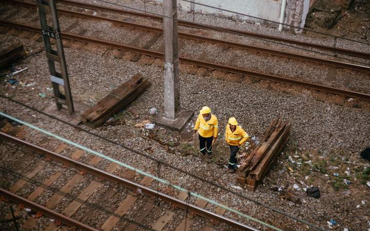 Agents de maintenance en tenue jaune intervenant entre les voies ferrées près de traverses