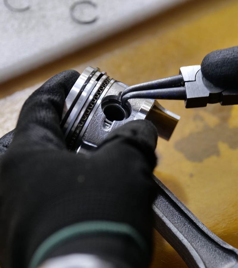 Main gantée utilisant une pince à circlips sur une pièce mécanique