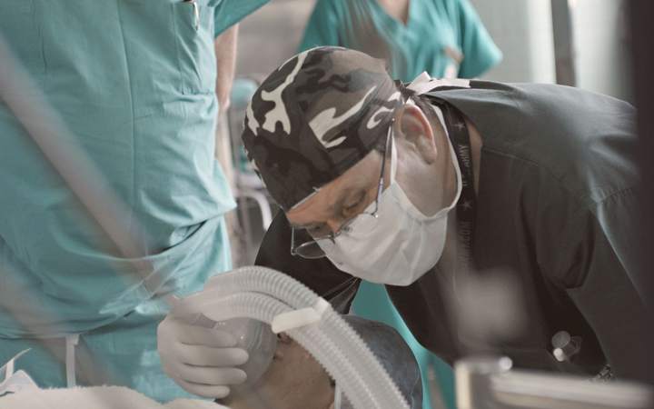 Anesthésiste masqué manipulant un circuit respiratoire au bloc opératoire