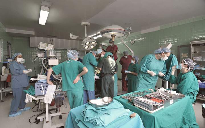 Équipe chirurgicale masquée au travail dans un bloc opératoire aux murs verts