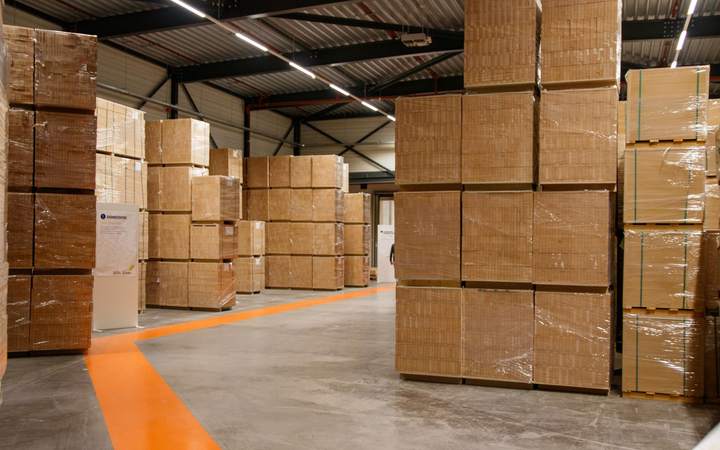 Palettes de cartons empilées dans un entrepôt au sol marqué d’une ligne orange
