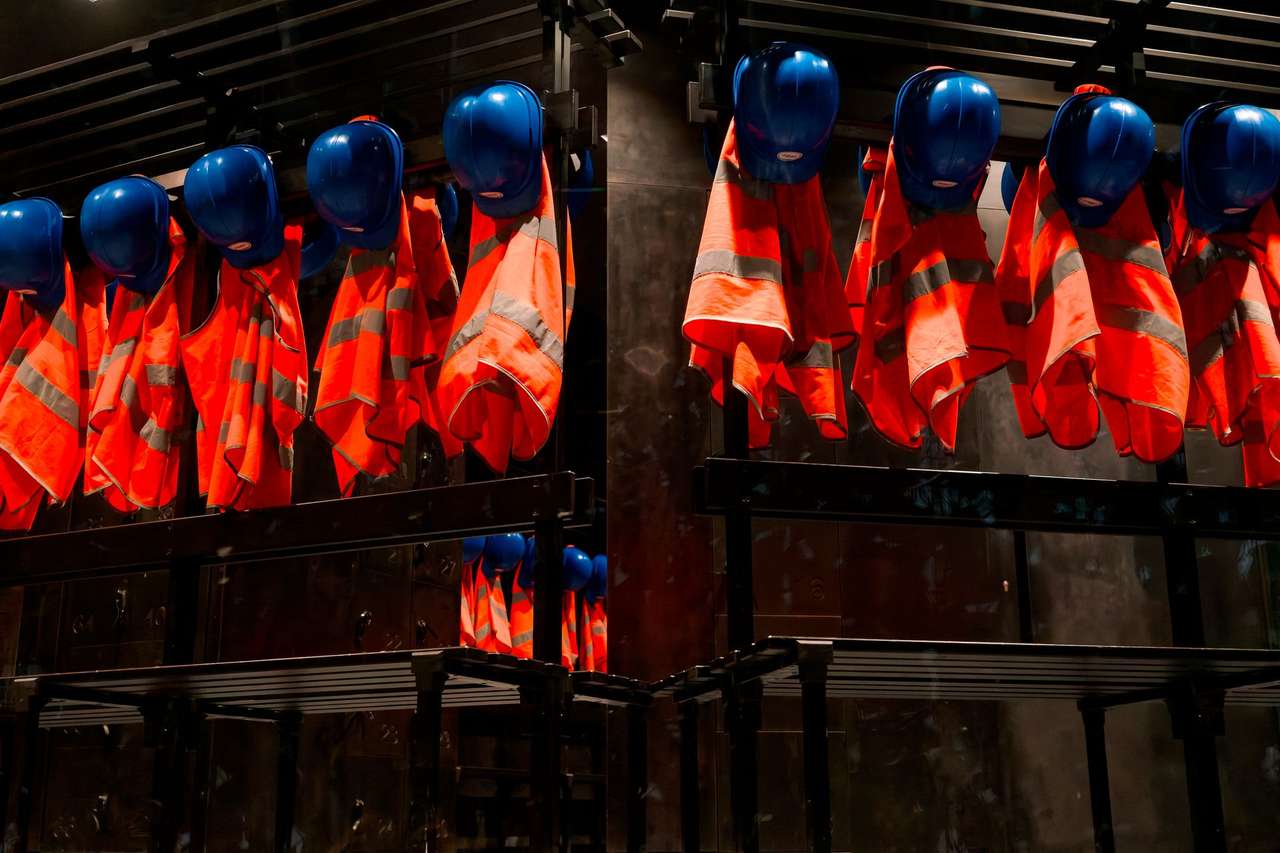 Casques bleus et vestes orange haute visibilité suspendus sur des portants dans un vestiaire