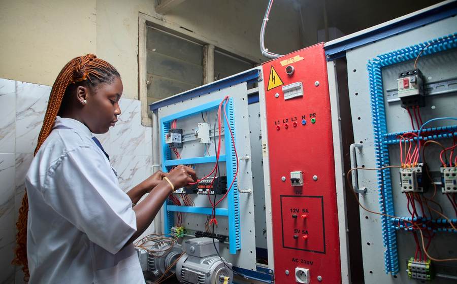 Technicienne en blouse câblant une maquette pédagogique d’armoire électrique