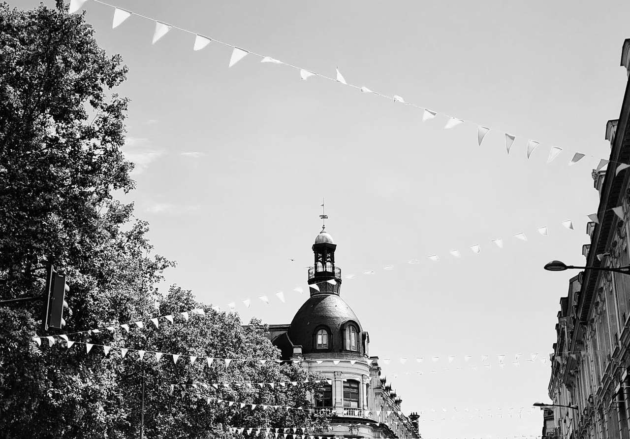Rue du centre de Troyes pavoisée de fanions, avec un immeuble à dôme, en noir et blanc