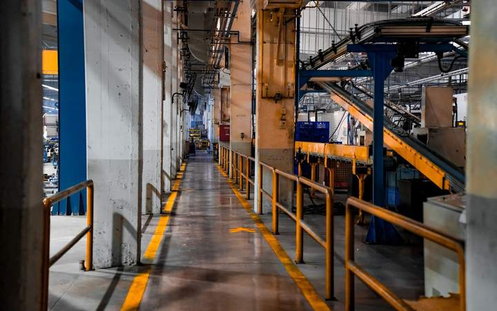 Allée d’usine bordée de garde-corps jaunes et de convoyeurs