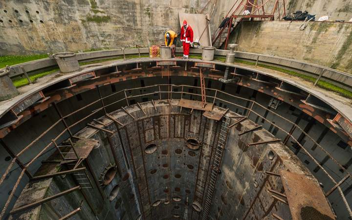 Ouvriers au bord d’un puits d’accès circulaire profond sur un chantier souterrain