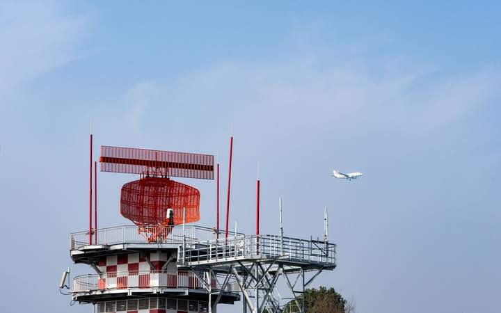 Radar de contrôle aérien rouge et blanc, avion en approche au loin