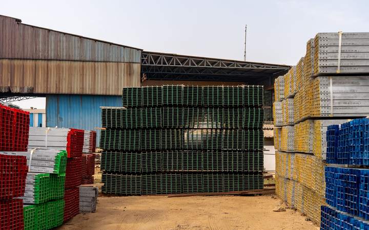 Aire de stockage extérieure avec piles de matériaux et d’éléments d’échafaudage devant un hangar