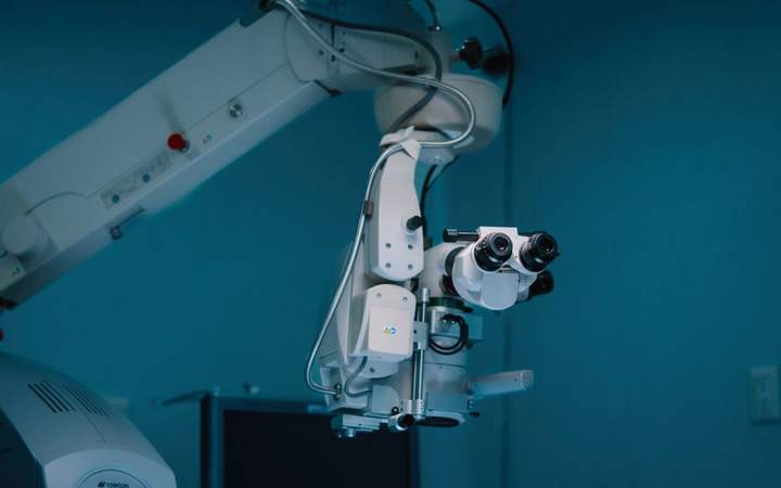 Microscope opératoire et scialytique dans une salle de chirurgie bleutée