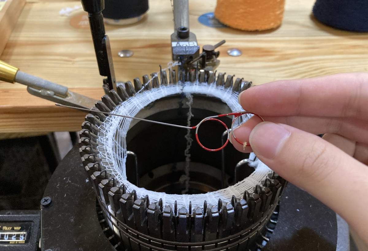 Mains réparant le bobinage d’un moteur électrique posé sur un établi en bois