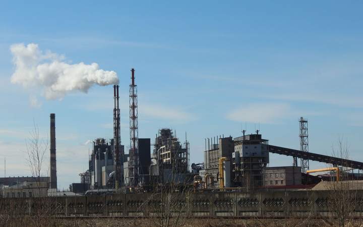 Usine chimique avec cheminées et panache de vapeur sous un ciel bleu