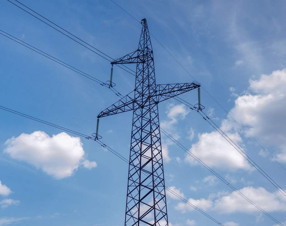 Pylône électrique et lignes aériennes sous un ciel bleu nuageux