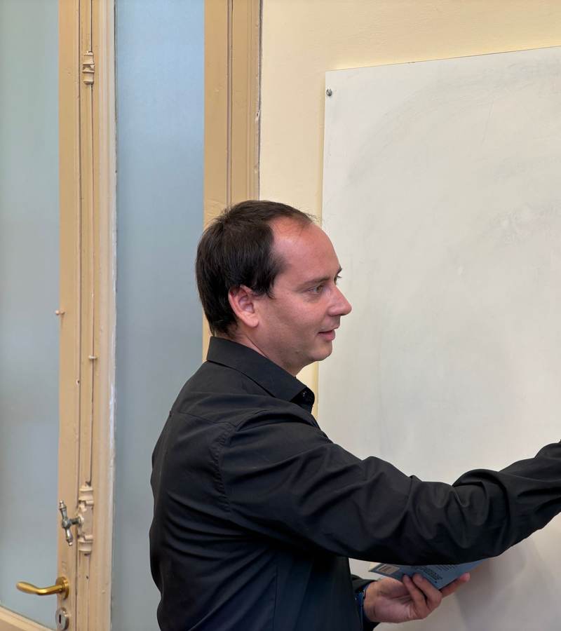 Formateur de profil écrivant au feutre sur un tableau blanc dans une salle