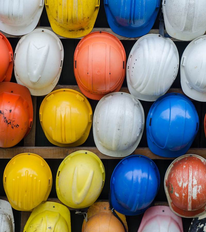 Casques de chantier de couleurs variées rangés en rangées sur un présentoir mural