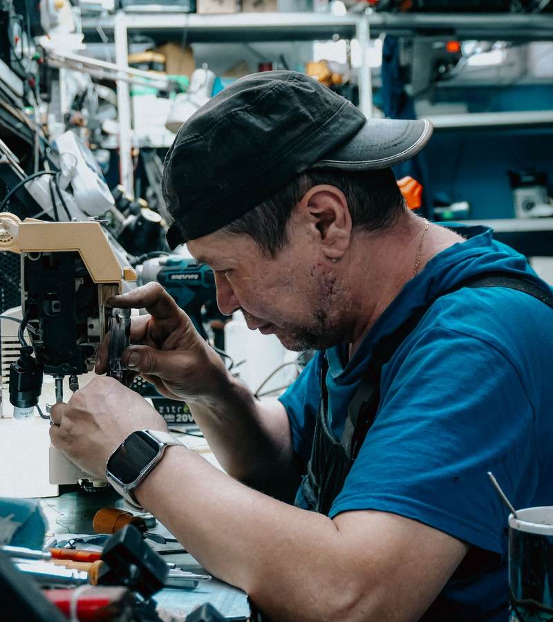Technicien concentré réparant un appareil sur un établi de maintenance encombré d’outils