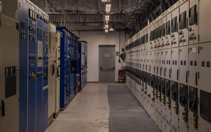 Local technique avec armoires électriques bleues et grises de part et d’autre