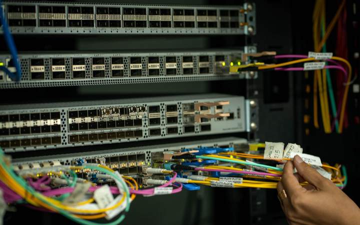 Technicien branchant des câbles de fibre optique colorés sur des commutateurs réseau en baie