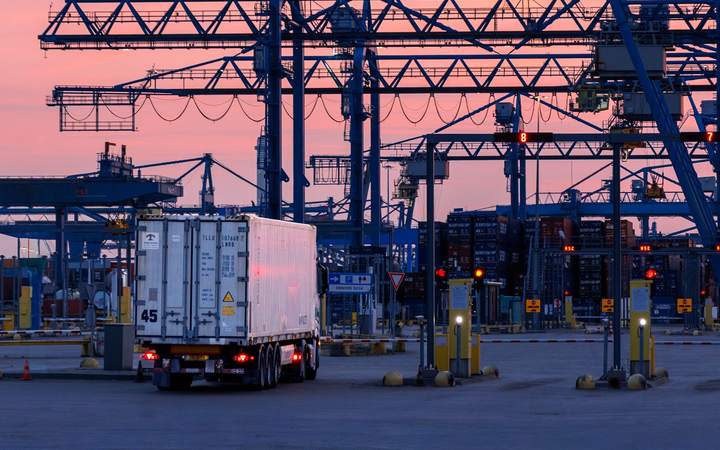 Camion frigorifique circulant sous les portiques d’un terminal à conteneurs au crépuscule