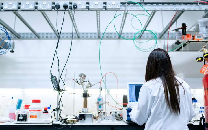 Chercheuse de dos travaillant devant un montage expérimental avec tuyaux et câbles au laboratoire
