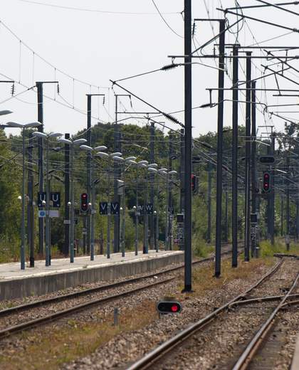 Voies ferrées et caténaires électrifiées le long d’un quai de gare