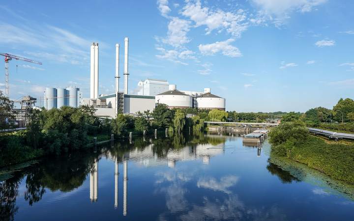 Centrale industrielle avec hautes cheminées et réservoirs, au bord d’un canal