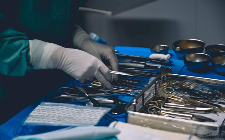 Mains gantées préparant des instruments chirurgicaux sur une table stérile