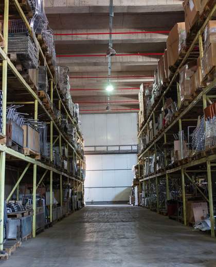 Allée d’entrepôt logistique bordée de rayonnages et d’éclairages