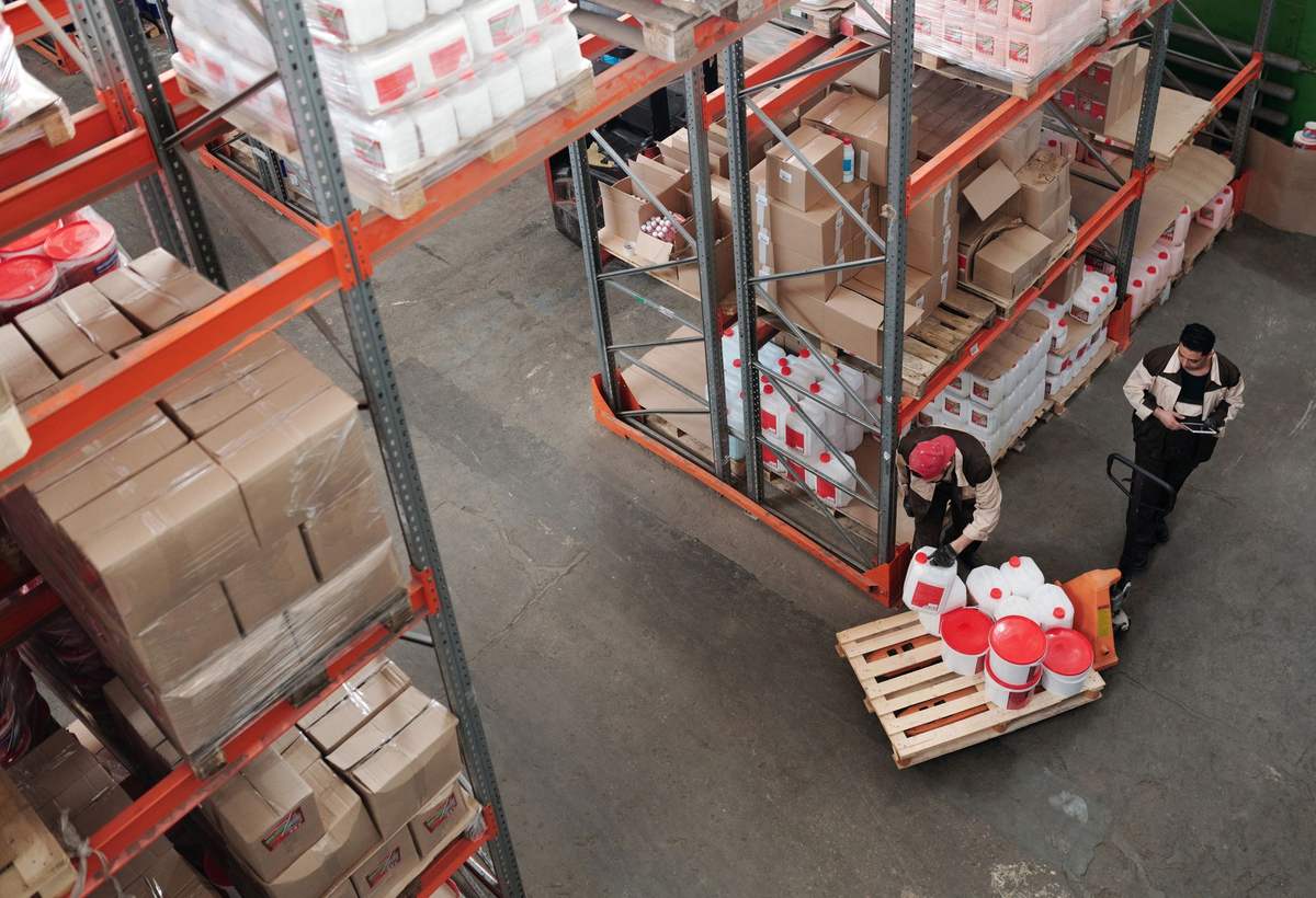 Deux employés d’entrepôt préparant une palette entre des rayonnages
