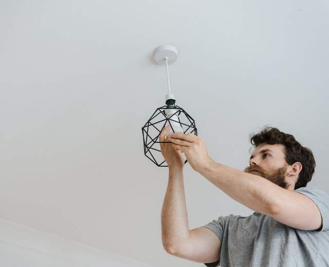 Pose d’un luminaire au plafond d’une pièce blanche