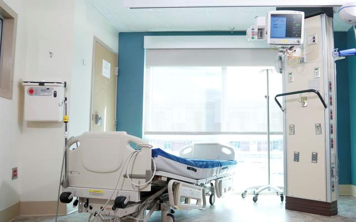 Chambre de soins avec lit médicalisé, bras de plafond et baie vitrée