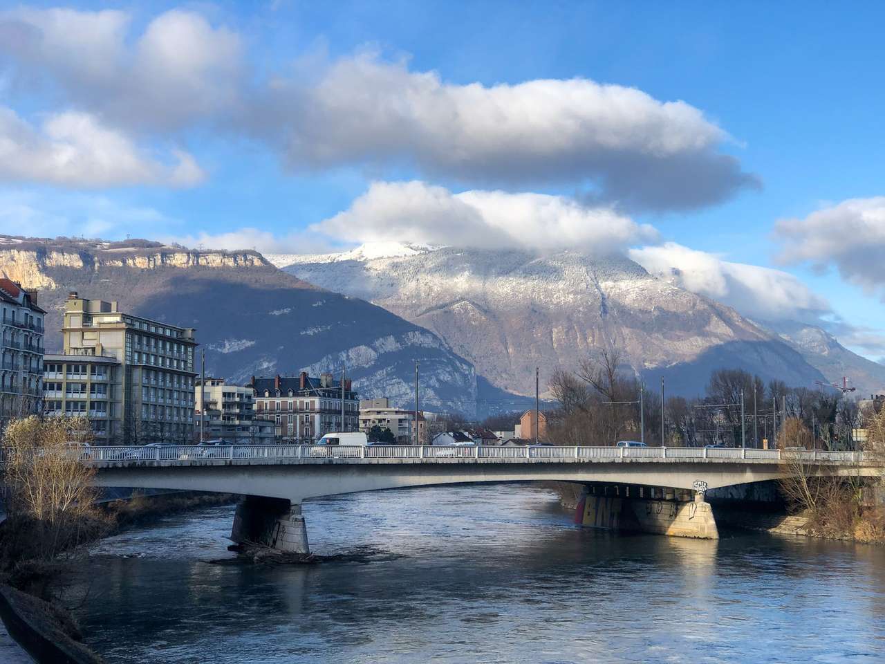 Pont routier sur la rivière à Grenoble, face à des montagnes enneigées