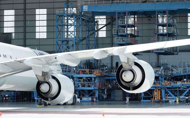 Aile et réacteurs d’un gros-porteur dans un hangar de maintenance avec passerelles