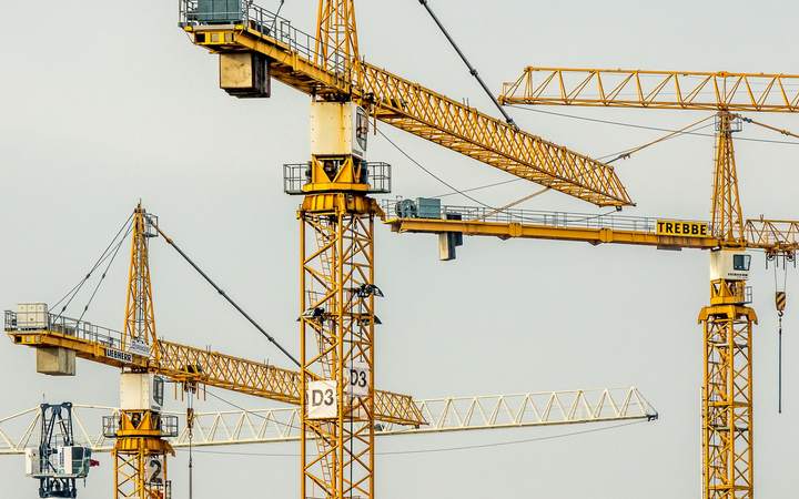 Grues de chantier jaunes entrecroisées sous un ciel clair
