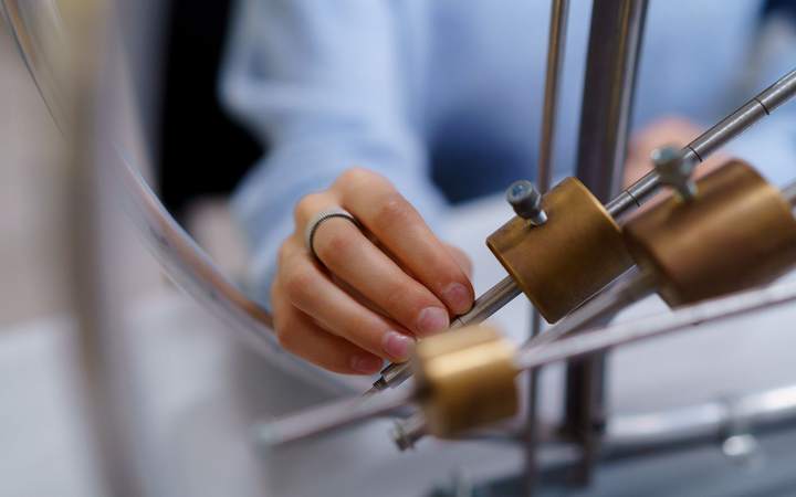 Mains réglant les masses d’un montage expérimental de physique dans un laboratoire de recherche