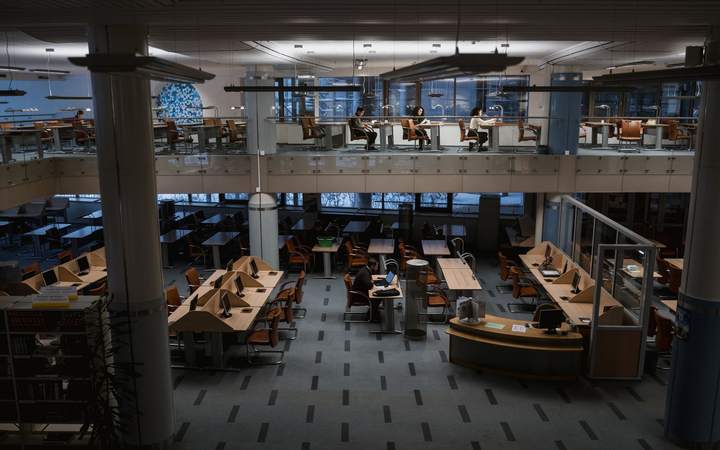 Grande salle de lecture sur deux niveaux d’une bibliothèque universitaire avec postes de travail