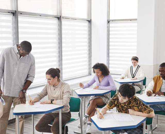 Formateur accompagnant des stagiaires pendant une évaluation écrite