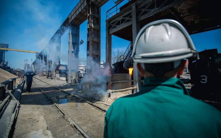 Ouvrier casqué vu de dos observant une installation industrielle en fonctionnement