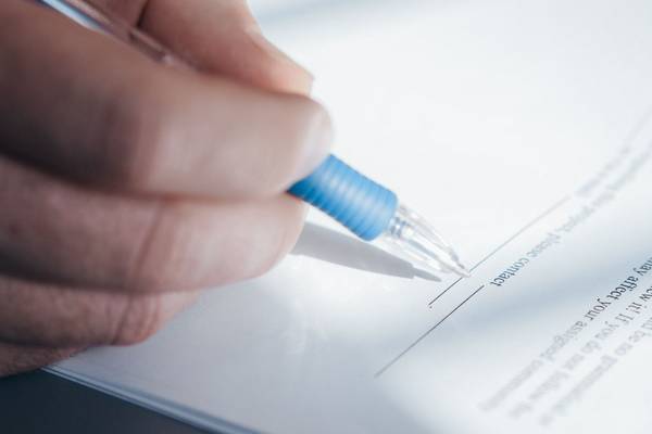 Gros plan sur une main signant un document au stylo bille bleu