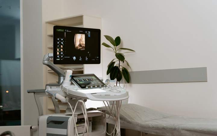 Échographe moderne avec écran et console à côté d’une table d’examen dans un cabinet