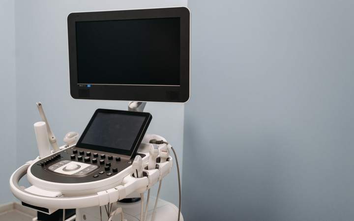 Échographe sur chariot avec écran et pavé tactile dans une salle d’examen aux murs bleus