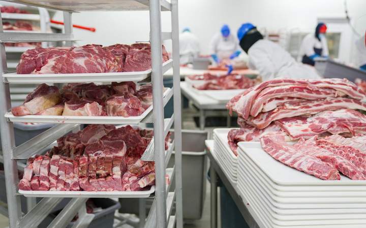 Atelier de découpe de viande avec chariots de pièces et opérateurs en tenue d’hygiène