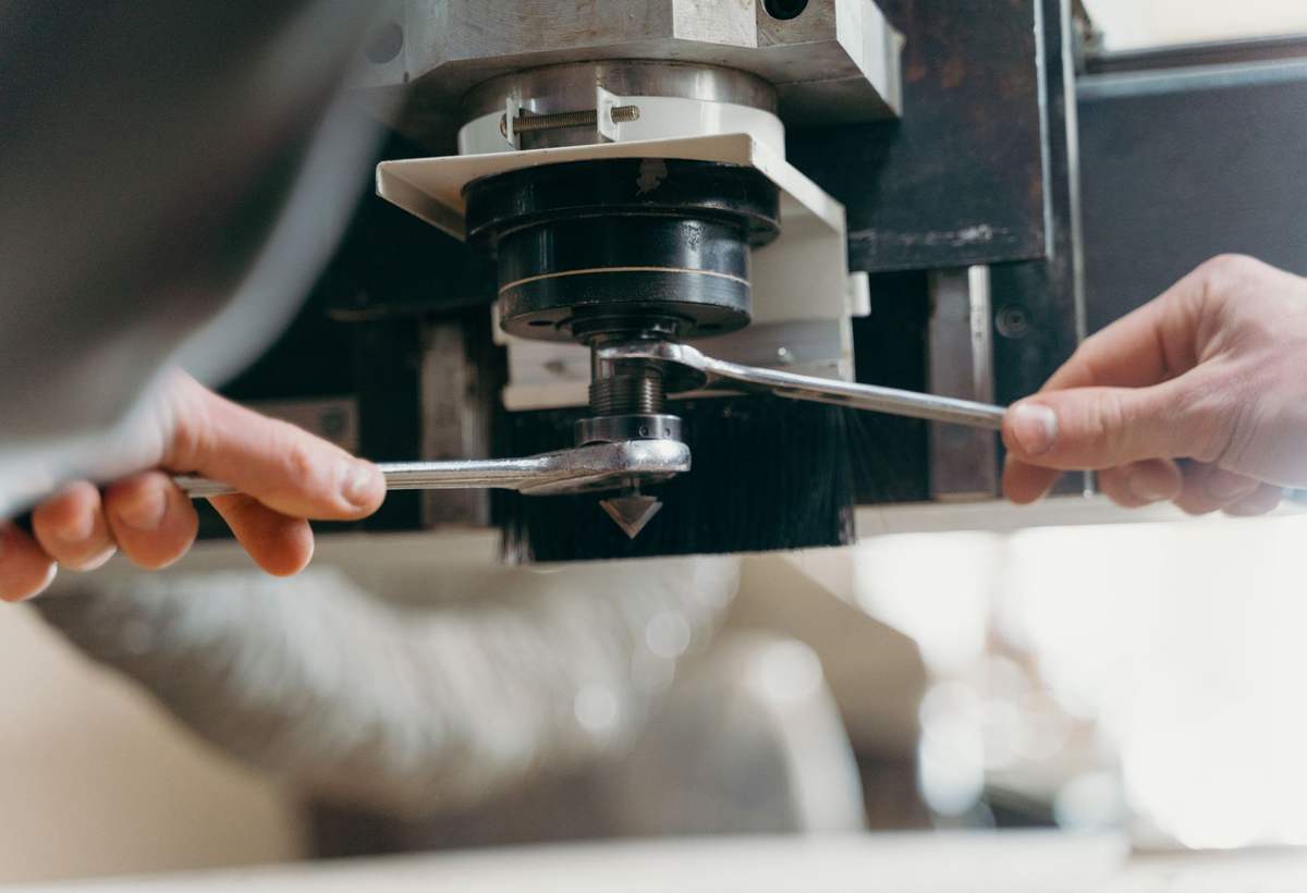 Mains réglant une broche de machine avec deux clés plates dans un atelier lumineux