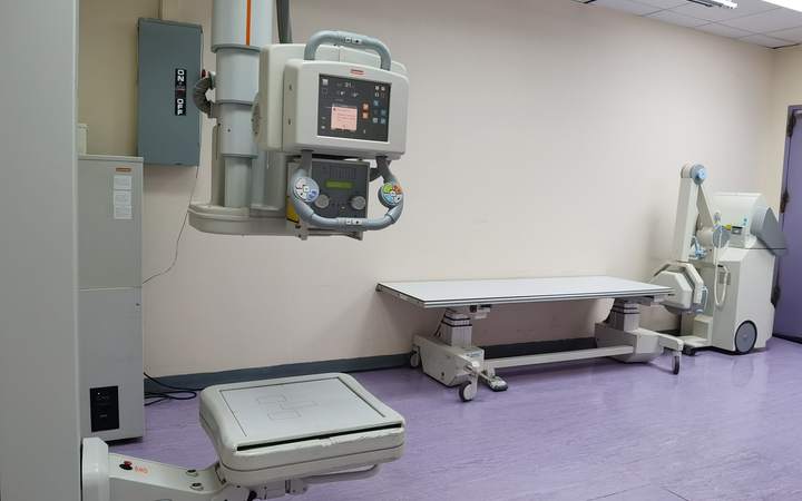 Salle de radiologie avec potence de radiographie, table d’examen et appareil mobile