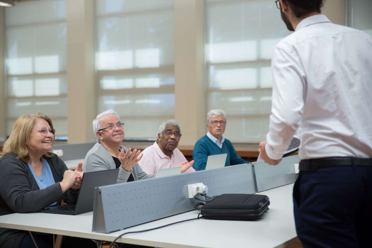 Formateur de dos s’adressant à des adultes attentifs installés devant des ordinateurs portables
