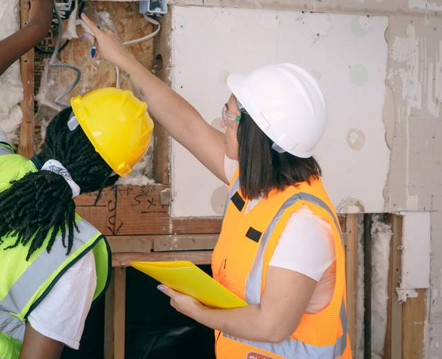 Deux techniciennes casquées examinant une installation électrique en rénovation