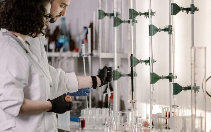 Chercheurs en blouse blanche manipulant des burettes et de la verrerie dans un laboratoire