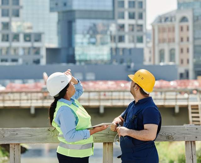 Deux professionnels casqués observent l’avancement d’un chantier en ville